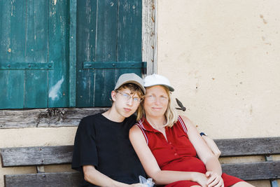 Portrait of young couple sitting against wall