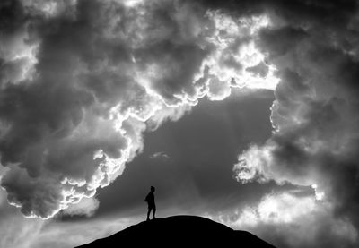 Silhouette of people standing against cloudy sky