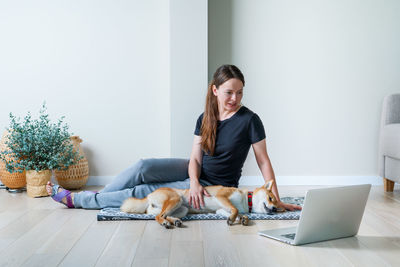 Young woman with dog  looking at camera of laptop and studying online