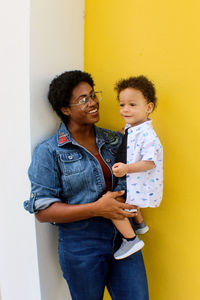 Woman  standing against wall holding baby