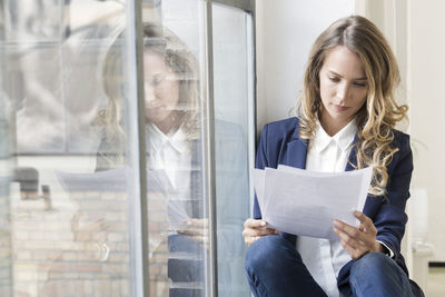 Businesswoman sitting in her office, reading papers