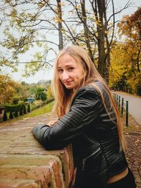 Portrait of beautiful woman standing in park against sky