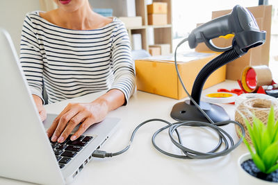 Midsection of woman using laptop on table