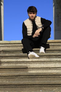 Low angle portrait of young man sitting on staircase