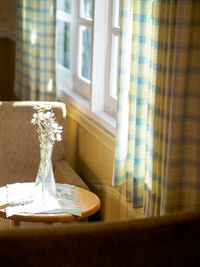 Flower vase on table by window at home