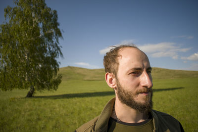 Young man looking away on land against sky