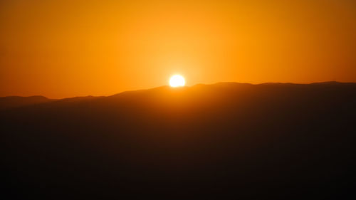 Scenic view of silhouette mountains against orange sky