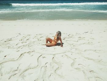 High angle view of young woman sitting on sand at beach