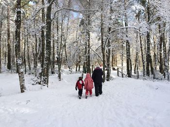 Rear view of family walking at snow covered forest