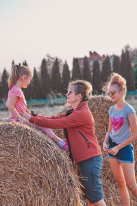 People on land by hay bale against clear sky