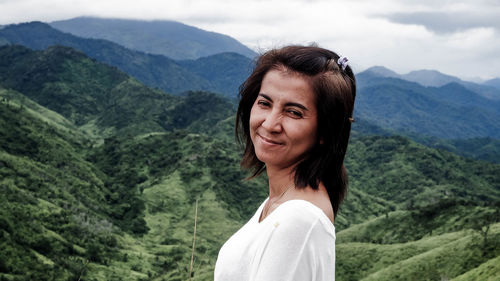 Portrait of young woman standing against mountain