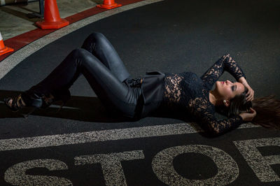 High angle view of woman lying road with stop text 