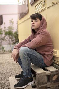 Portrait of young teen sitting against motor home while looking camera