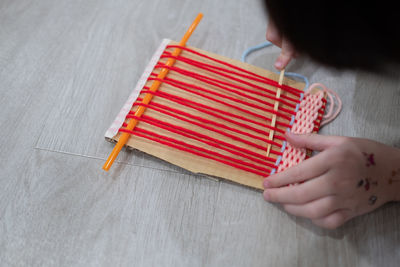 Cropped hand of woman holding colored pencils on table