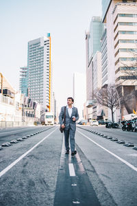 Full length of businessman walking on road against building