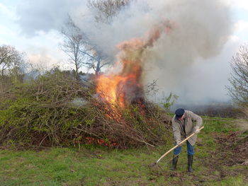 Farmer with gardening fork working by bonfire