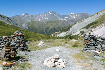 Stack of stones on snow covered mountain against sky