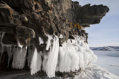 Panoramic view of icicles on rock against sky