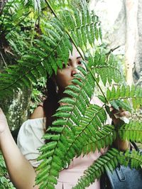 Close-up of woman with leaves on tree