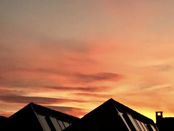 Low angle view of silhouette house against sky during sunset