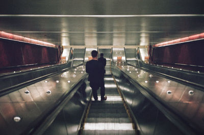 Rear view of man standing on escalator at subway station