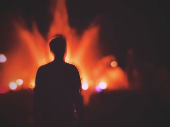 Rear view of silhouette man standing against sky at night