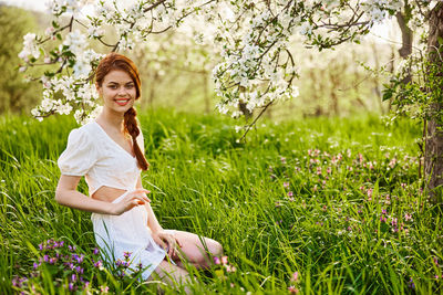 Portrait of young woman standing on grassy field