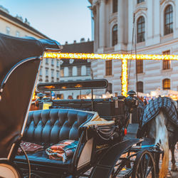 Illuminated horse cart on street against buildings in city