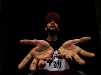 Portrait of young man standing against black background