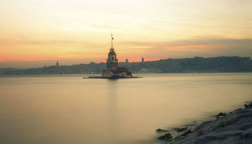 Maiden tower in sea against sky during sunset