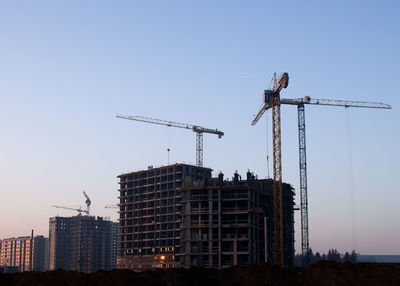 Low angle view of crane at construction site against sky