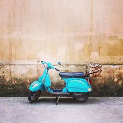 Side view of motor scooter parked against wall