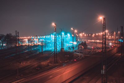 High angle view of illuminated railroad tracks against clear sky at night