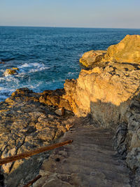 Rocks on shore by sea against sky