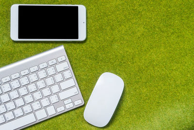 High angle view of keyboard and mobile phone on grass