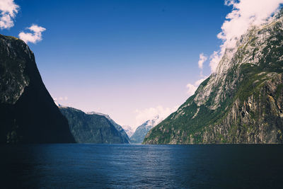 Scenic view of sea by mountains against sky