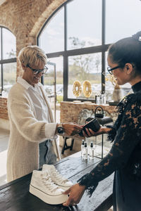 Female customer paying via tap to pay method at checkout in store
