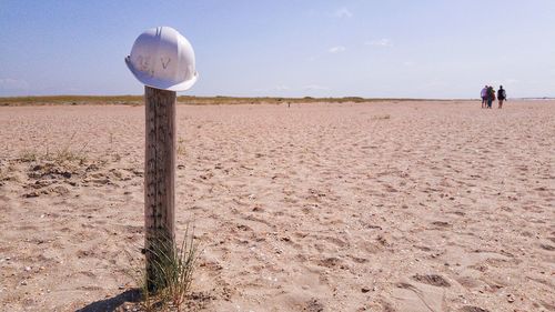 View of wooden posts on sand at beach against sky