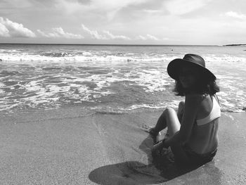 Woman in hat relaxing on shore at beach