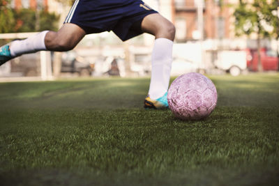 Low section of athlete kicking ball at soccer field