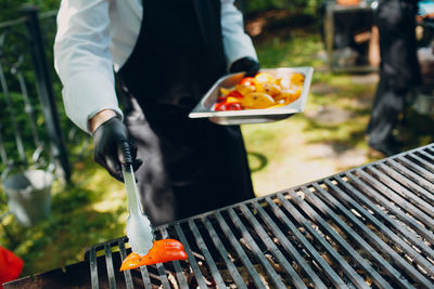 Midsection of man standing on barbecue grill in yard