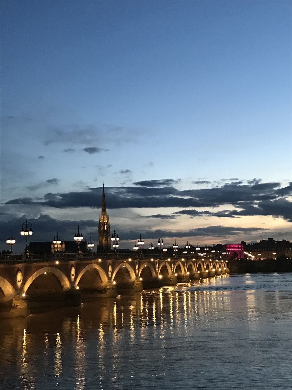 ILLUMINATED BRIDGE OVER RIVER AGAINST SKY