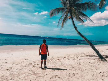 Rear view of man on beach against sky