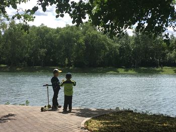 Rear view of people on lake against trees