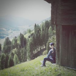 Side view of man sitting on road amidst trees