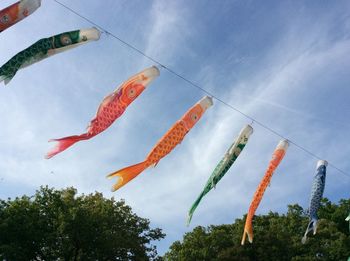 Low angle view of fishes decoration hanging against sky
