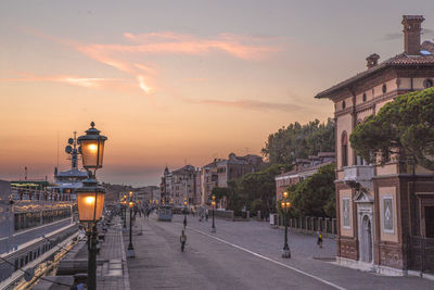 Street light on road against buildings at sunset