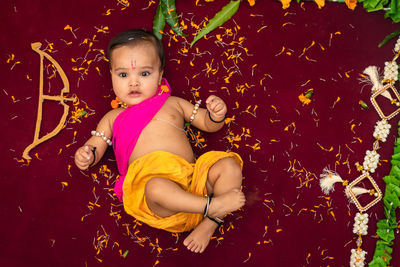 Cute indian boy dresses as lord rama with bow and flowers from top angle