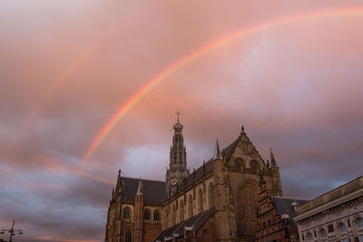 Low angle view of rainbow over city against sky