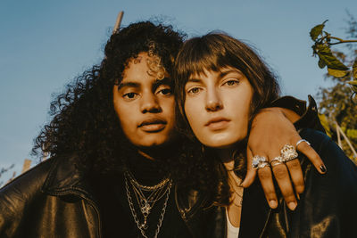 Portrait of female friends with arm around outdoors on sunny day